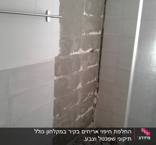 קיר עם אריחים שבורים בתהליך שיפוץ